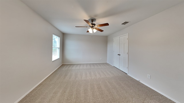 spare room featuring baseboards, light carpet, a ceiling fan, and visible vents