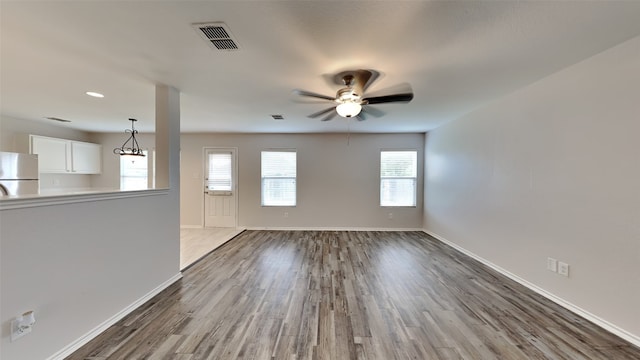 unfurnished living room featuring visible vents, a ceiling fan, baseboards, and dark wood-type flooring