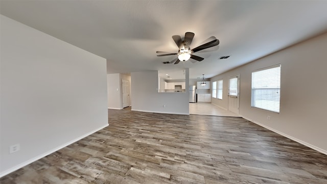 unfurnished living room featuring a ceiling fan, baseboards, visible vents, and wood finished floors