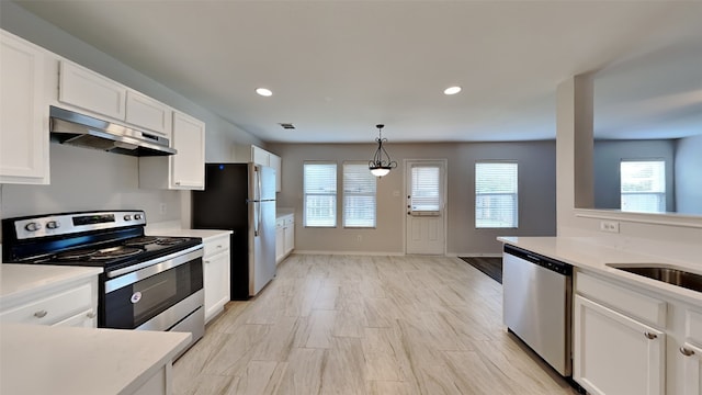 kitchen featuring pendant lighting, light countertops, under cabinet range hood, white cabinets, and stainless steel appliances