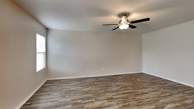 spare room featuring ceiling fan, dark wood-style floors, and baseboards