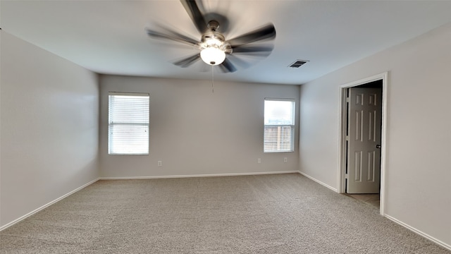 carpeted spare room featuring baseboards, ceiling fan, and visible vents