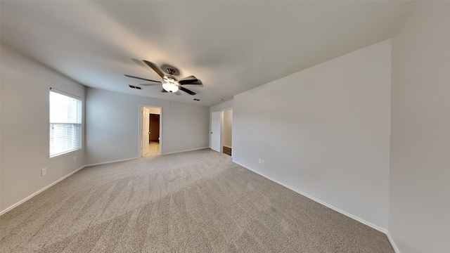 spare room with light colored carpet, a ceiling fan, baseboards, and visible vents