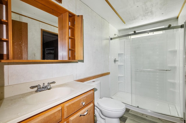 bathroom with toilet, a shower stall, wood finished floors, and vanity