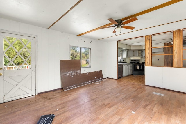 unfurnished living room with a ceiling fan, baseboards, plenty of natural light, and light wood-type flooring