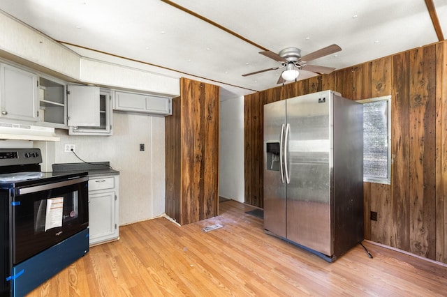 kitchen featuring range with electric stovetop, ceiling fan, wooden walls, stainless steel fridge, and under cabinet range hood