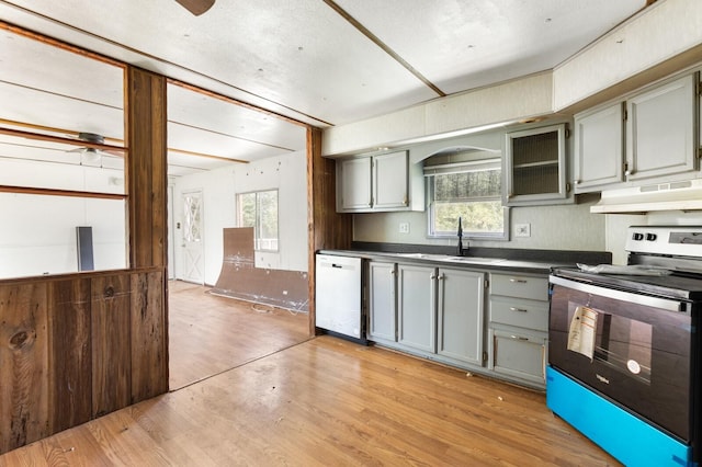 kitchen with under cabinet range hood, a sink, dishwasher, gray cabinetry, and stainless steel electric range oven