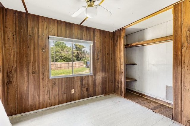 unfurnished bedroom featuring a closet, a ceiling fan, and wood walls