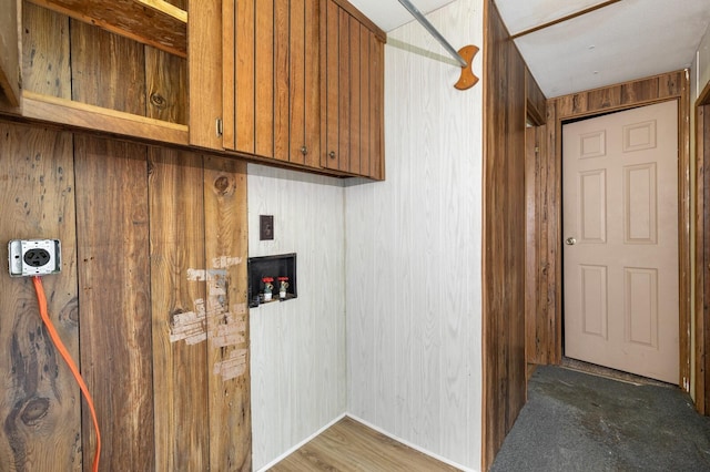 clothes washing area with cabinet space, wooden walls, and hookup for a washing machine
