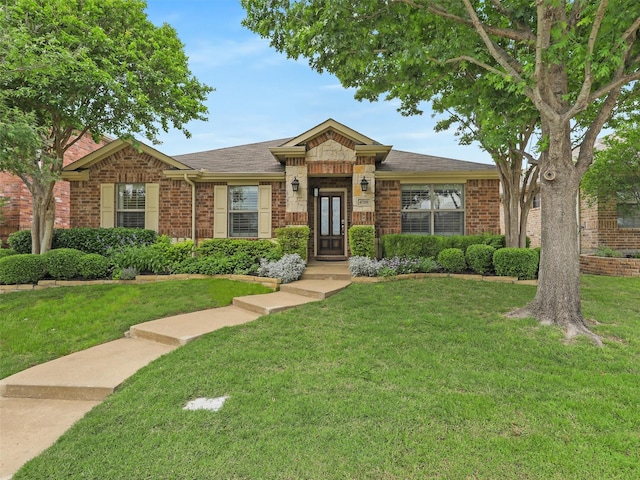 single story home with roof with shingles, a front yard, and brick siding