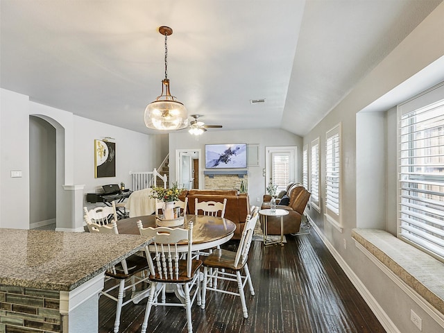 dining room featuring arched walkways, a ceiling fan, baseboards, vaulted ceiling, and dark wood-style floors