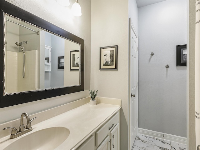 full bath with vanity, marble finish floor, baseboards, and a shower