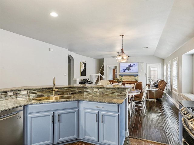 kitchen featuring appliances with stainless steel finishes, a sink, arched walkways, open floor plan, and vaulted ceiling
