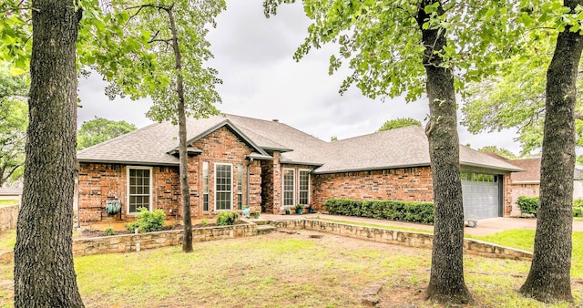 ranch-style house featuring roof with shingles, an attached garage, a front lawn, and brick siding
