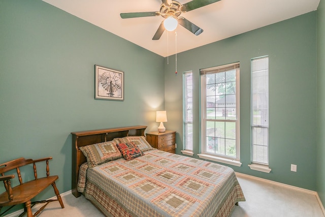 carpeted bedroom featuring baseboards, multiple windows, and a ceiling fan