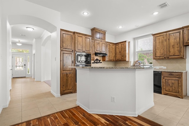 kitchen with brown cabinetry, decorative backsplash, visible vents, a healthy amount of sunlight, and black appliances