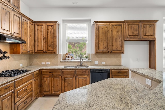 kitchen featuring light stone counters, a sink, under cabinet range hood, and black appliances