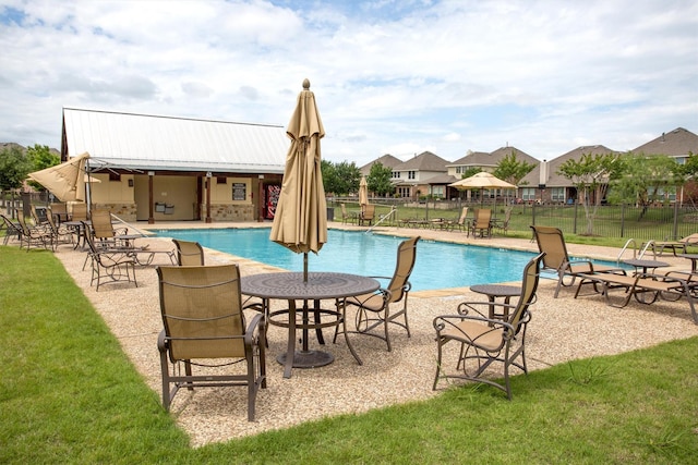 pool featuring a lawn, fence, a residential view, and a patio area
