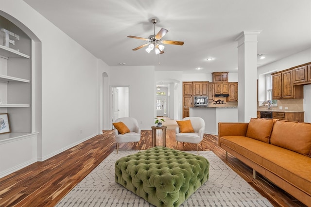 living area featuring a healthy amount of sunlight, arched walkways, a ceiling fan, and dark wood-style flooring