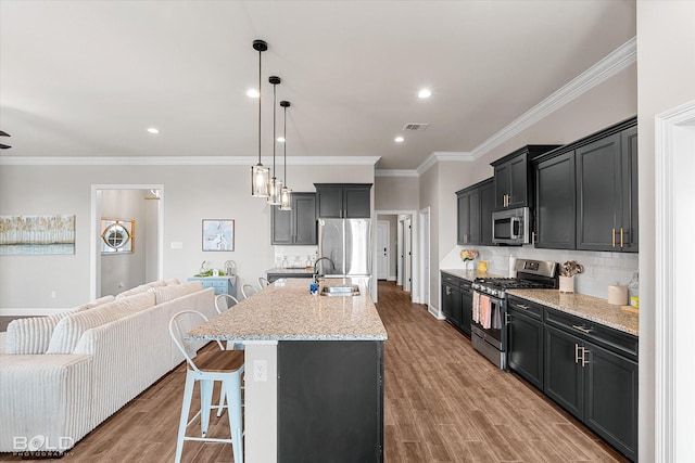 kitchen featuring a sink, stainless steel appliances, open floor plan, a kitchen bar, and visible vents