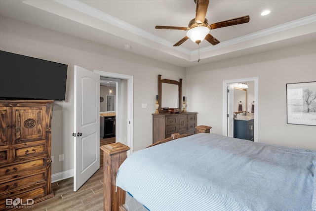 bedroom featuring ensuite bathroom, a raised ceiling, ornamental molding, recessed lighting, and light wood-style flooring
