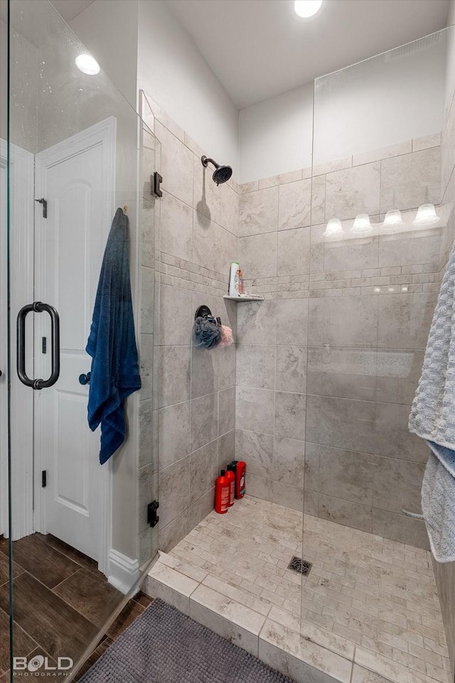 bathroom featuring wood finished floors and a shower stall