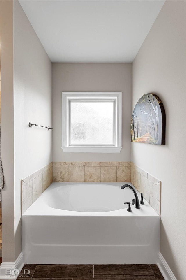 bathroom featuring baseboards, wood finished floors, and a garden tub