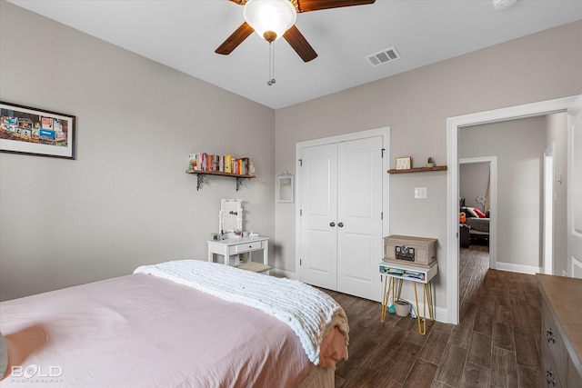 bedroom with a ceiling fan, baseboards, dark wood-type flooring, visible vents, and a closet