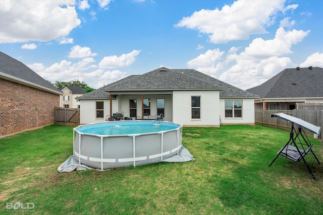 rear view of house with a yard, a fenced in pool, a fenced backyard, and roof with shingles