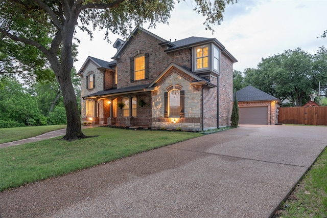 view of front facade featuring fence, a front lawn, stone siding, a garage, and a porch