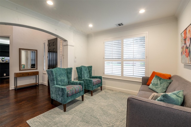 sitting room with arched walkways, baseboards, wood finished floors, visible vents, and ornamental molding