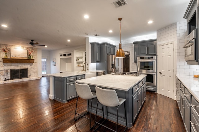 kitchen featuring ceiling fan, a kitchen island, visible vents, appliances with stainless steel finishes, and gray cabinetry