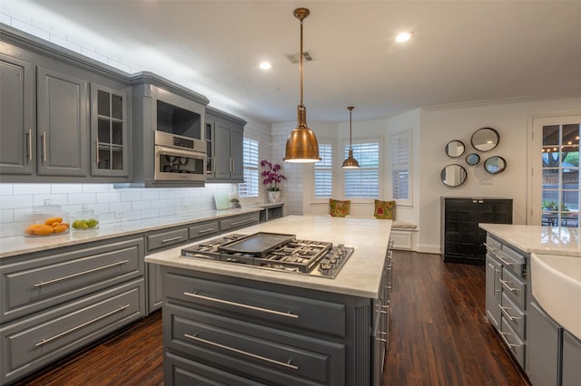 kitchen featuring decorative backsplash, gray cabinets, visible vents, stainless steel gas cooktop, and dark wood-type flooring