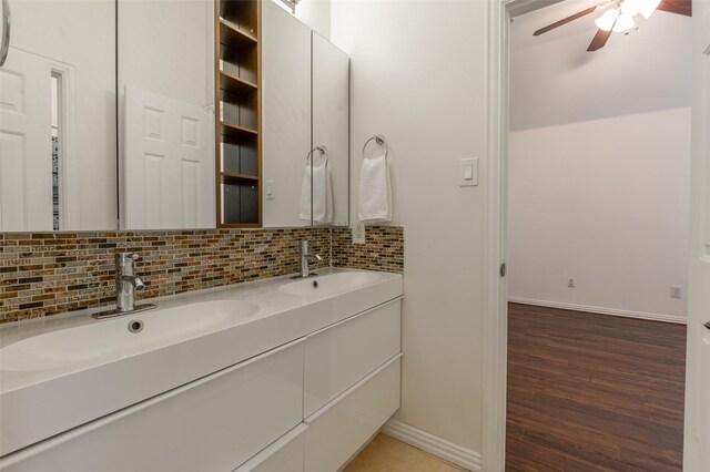 bathroom with wood finished floors, a sink, a ceiling fan, and backsplash