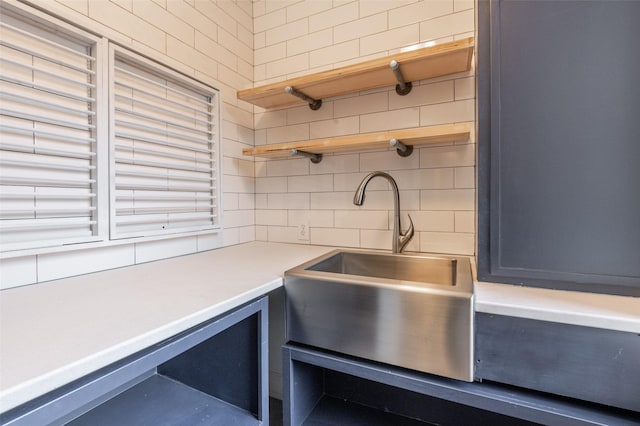 kitchen featuring a sink, light countertops, open shelves, and backsplash
