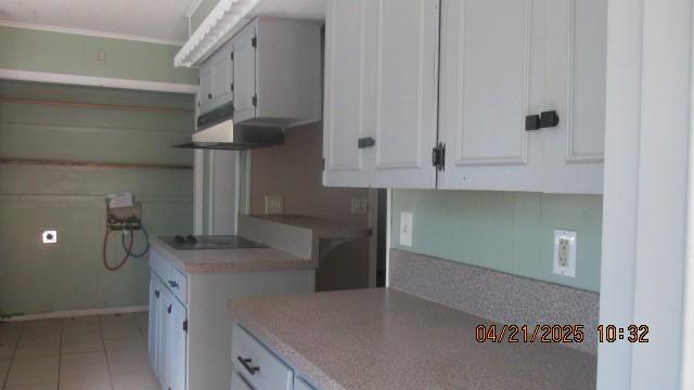 kitchen with white cabinets, black electric stovetop, light countertops, light tile patterned floors, and under cabinet range hood
