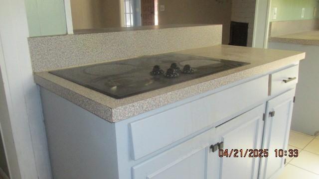 interior space with light countertops, light tile patterned floors, black electric stovetop, and white cabinetry