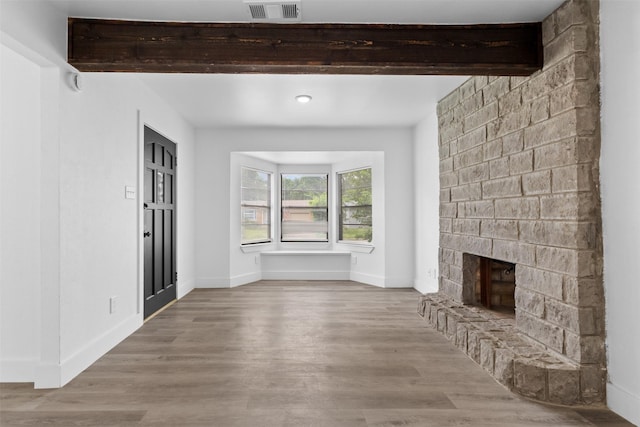 unfurnished living room with visible vents, baseboards, wood finished floors, and a large fireplace