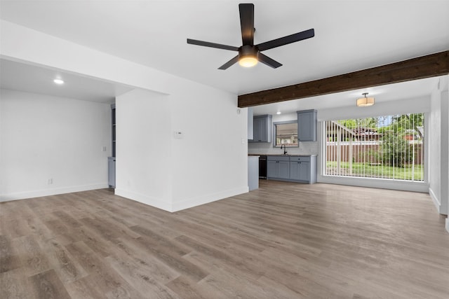 unfurnished living room featuring baseboards, beam ceiling, ceiling fan, and light wood-style flooring