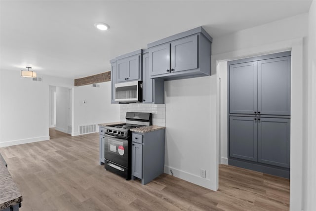 kitchen with visible vents, baseboards, black range with gas cooktop, light wood-type flooring, and backsplash