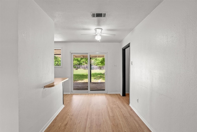 spare room with baseboards, a ceiling fan, light wood finished floors, and visible vents