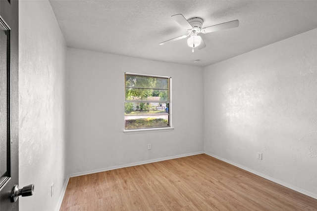 unfurnished room with a ceiling fan, baseboards, a textured ceiling, and light wood-style floors
