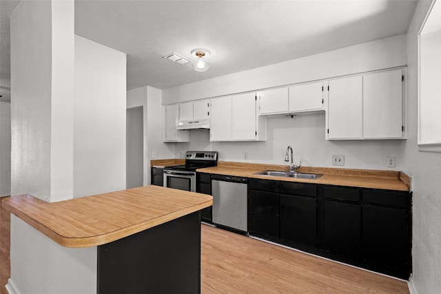 kitchen featuring visible vents, light wood-type flooring, a sink, under cabinet range hood, and stainless steel appliances