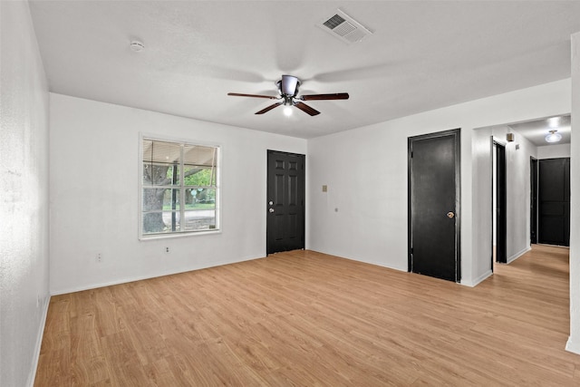 empty room with baseboards, a ceiling fan, light wood finished floors, and visible vents