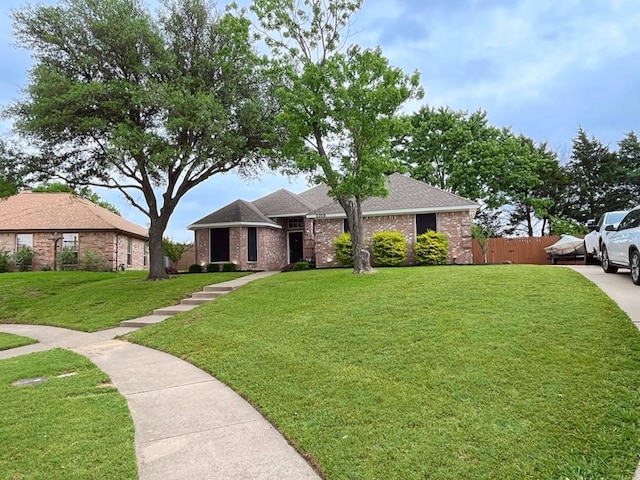 single story home with brick siding, fence, a shingled roof, and a front yard