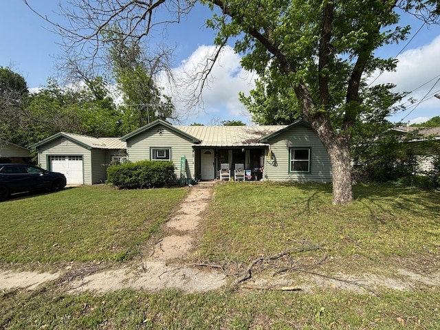 ranch-style house with covered porch, metal roof, a front yard, and a garage