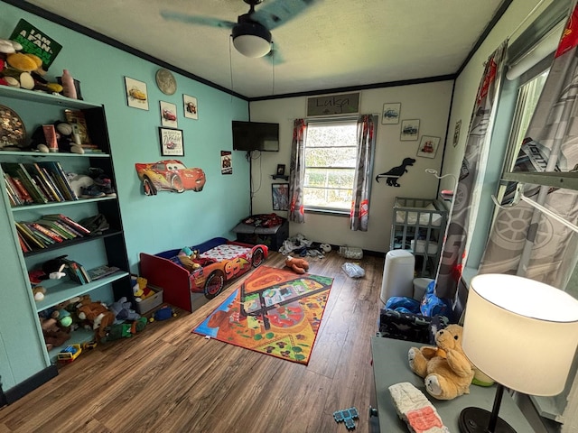 rec room with crown molding, ceiling fan, and wood finished floors