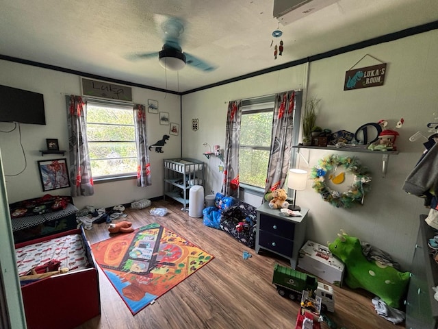 recreation room with a ceiling fan, ornamental molding, and wood finished floors