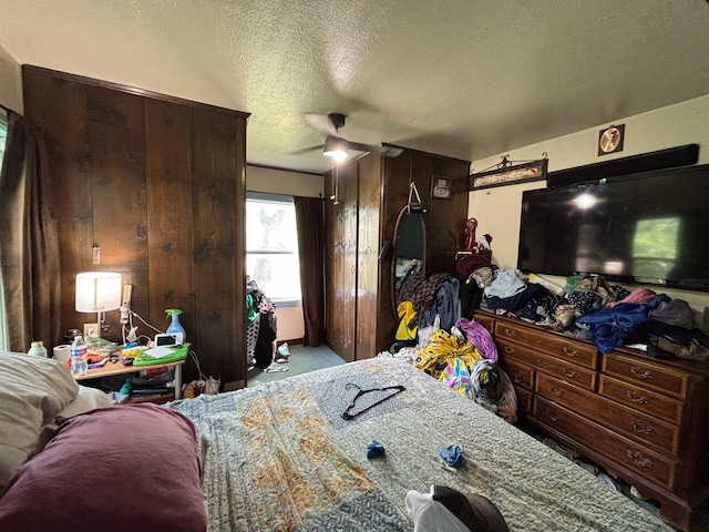 bedroom featuring wooden walls, carpet floors, and a textured ceiling