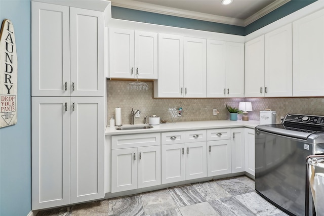 laundry room with cabinet space, crown molding, and a sink